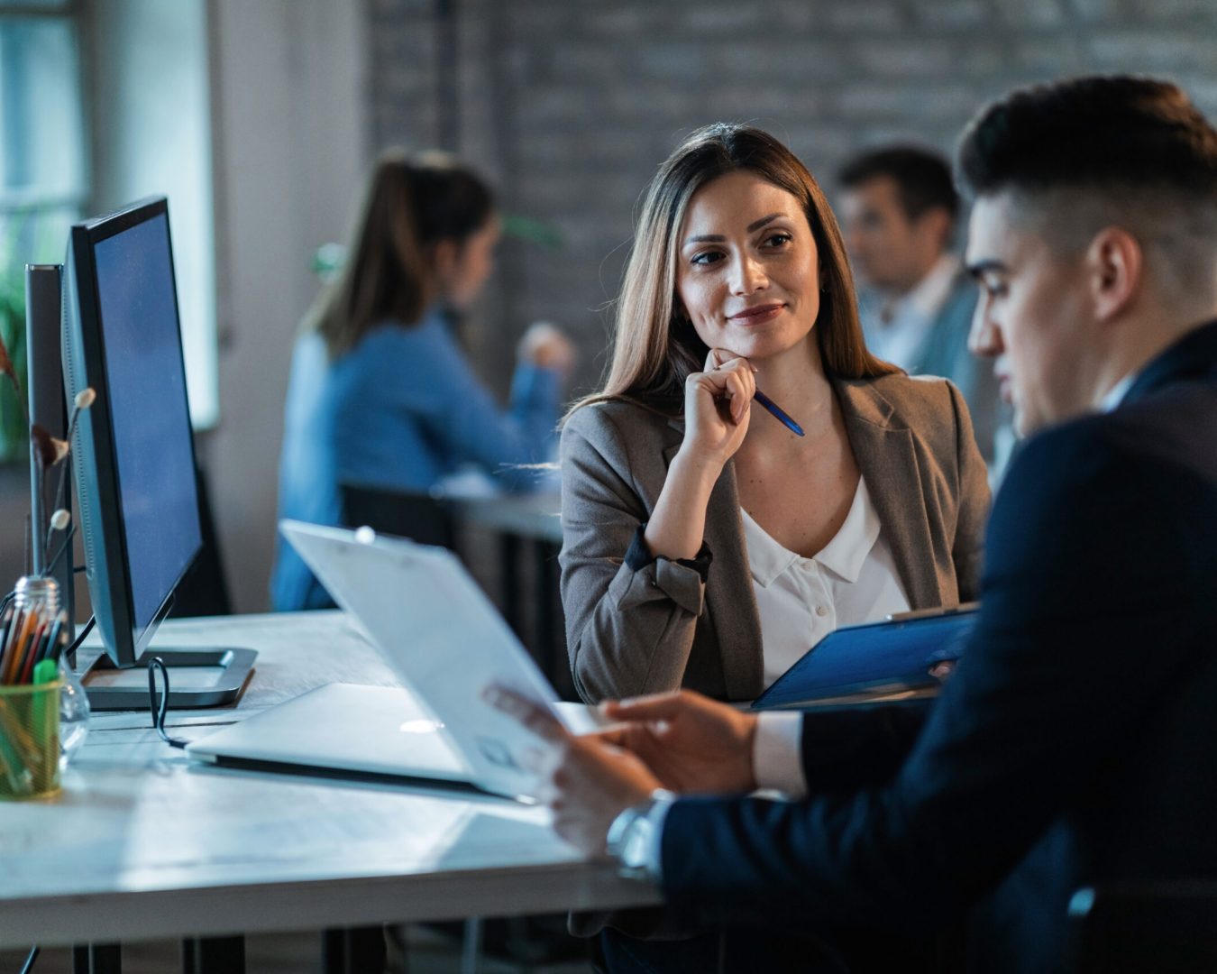Business colleagues working on reports and communicating while working in the office. Focus is on woman.